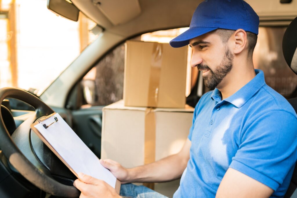 Delivery man checking delivery list in van.